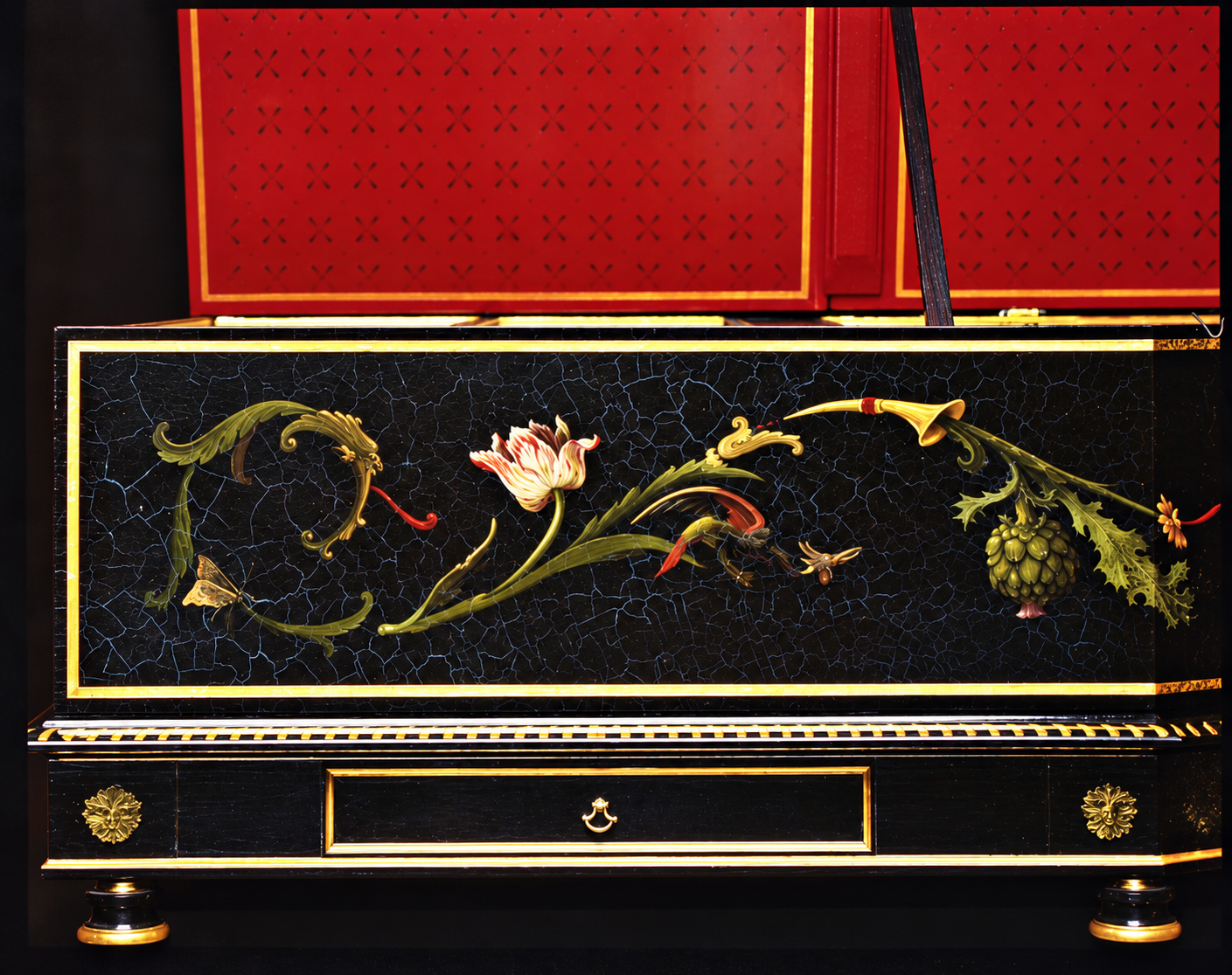 Detail of the Colmar Ruckers cheek panel — botanical painting with tulip, acanthus scrolls, butterfly and artichoke on a craquelure black ground with gold borders